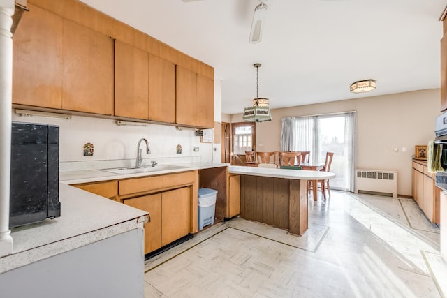 kitchen featuring radiator, light floors, light countertops, a peninsula, and a sink