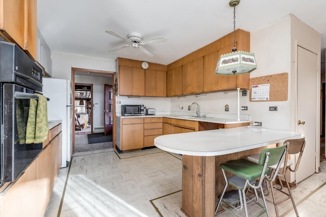 kitchen with a peninsula, freestanding refrigerator, a sink, stainless steel microwave, and black oven