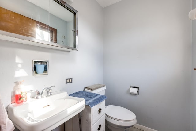 half bath with a sink, baseboards, and toilet