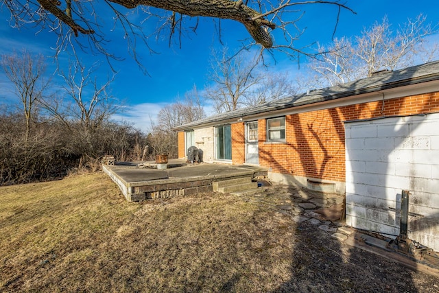 back of house with a lawn and brick siding