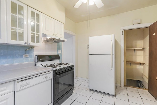 kitchen with under cabinet range hood, tasteful backsplash, white appliances, white cabinets, and light countertops