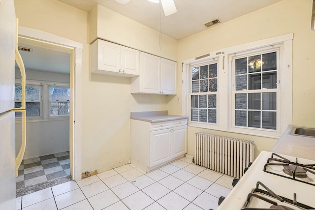 kitchen featuring a ceiling fan, visible vents, radiator heating unit, light countertops, and white cabinets