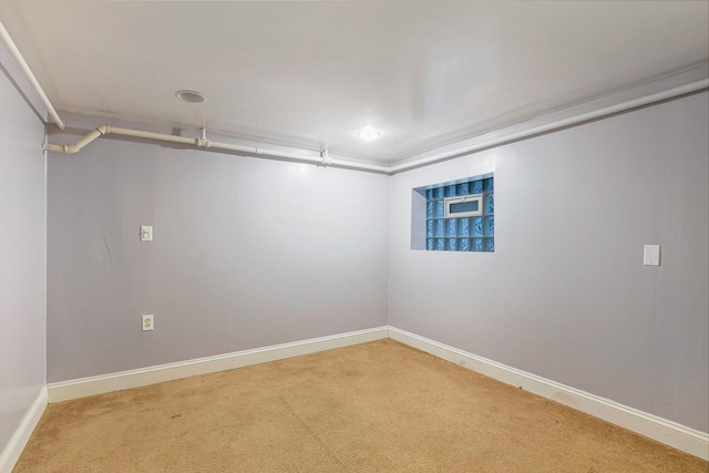 empty room featuring baseboards and light carpet