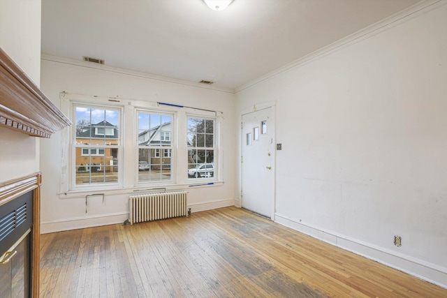 unfurnished room with visible vents, crown molding, radiator heating unit, and hardwood / wood-style flooring