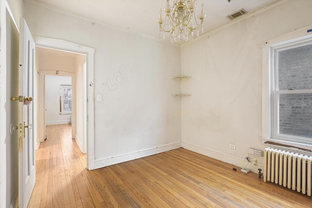 unfurnished room featuring visible vents, light wood finished floors, radiator heating unit, crown molding, and a chandelier