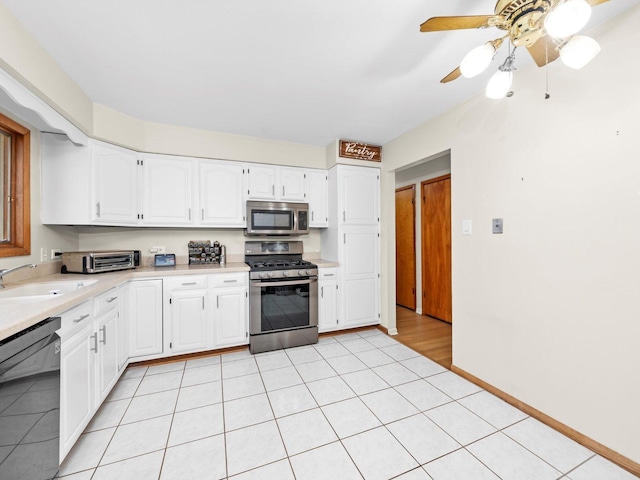 kitchen featuring light countertops, white cabinets, appliances with stainless steel finishes, and a sink