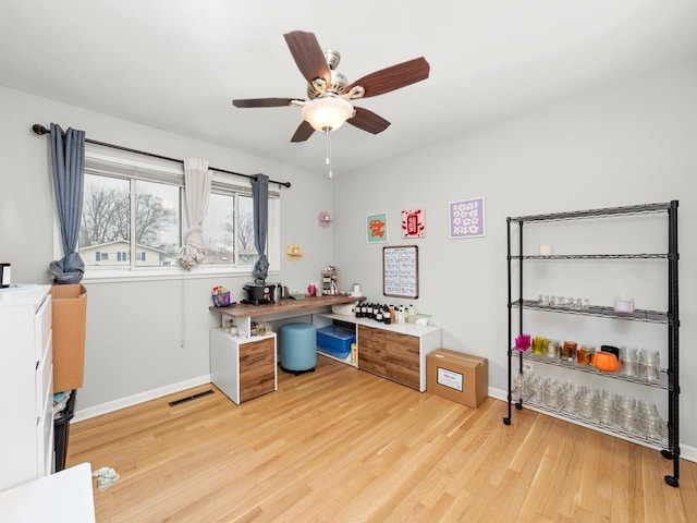 home office with visible vents, a ceiling fan, light wood-type flooring, and baseboards