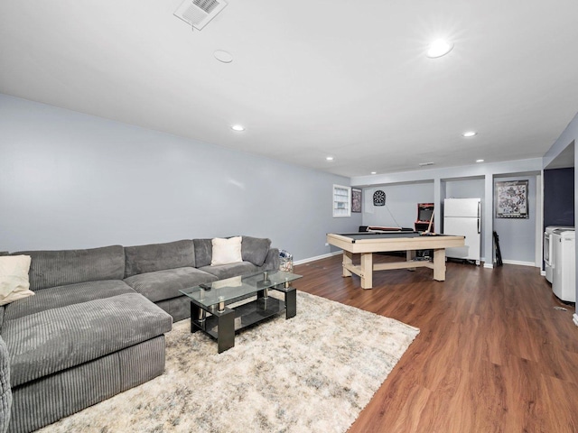 living area featuring washing machine and clothes dryer, visible vents, baseboards, recessed lighting, and wood finished floors