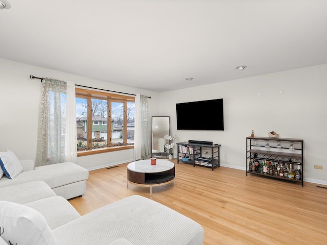 living room featuring visible vents, baseboards, and light wood-style floors