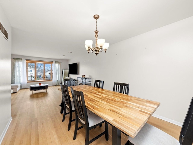 dining area featuring baseboards, light wood-style floors, and an inviting chandelier