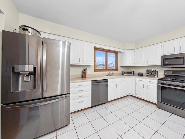 kitchen with a sink, white cabinetry, appliances with stainless steel finishes, light tile patterned flooring, and light countertops