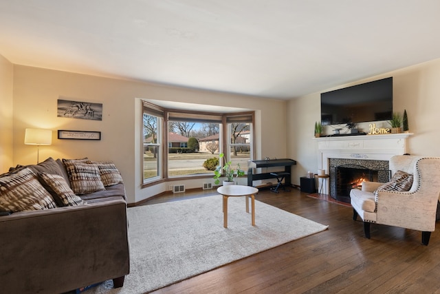 living area with a fireplace with flush hearth, wood finished floors, and visible vents