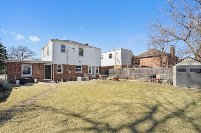 rear view of property featuring brick siding, fence, a yard, an outdoor structure, and a storage unit