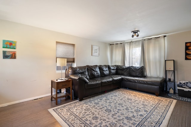 living room featuring visible vents, baseboards, and wood finished floors