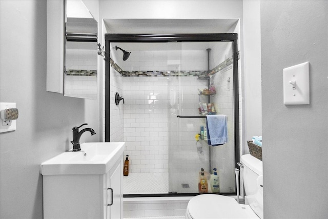 bathroom featuring vanity, a shower stall, and toilet