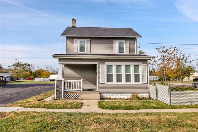 view of front of home with covered porch, a chimney, and fence