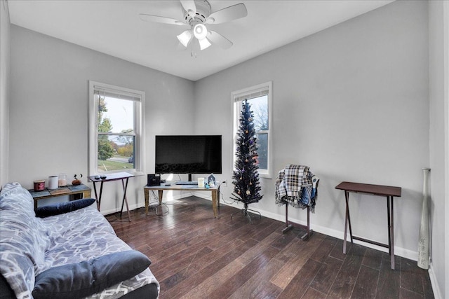 living area featuring baseboards, wood finished floors, and a ceiling fan