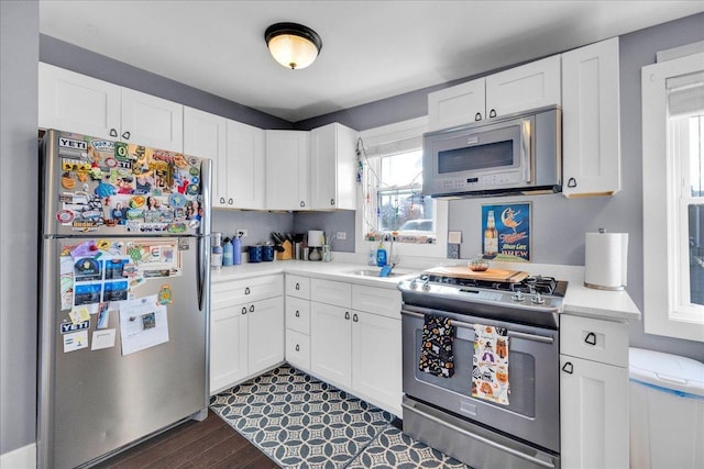 kitchen featuring a sink, appliances with stainless steel finishes, white cabinets, and light countertops