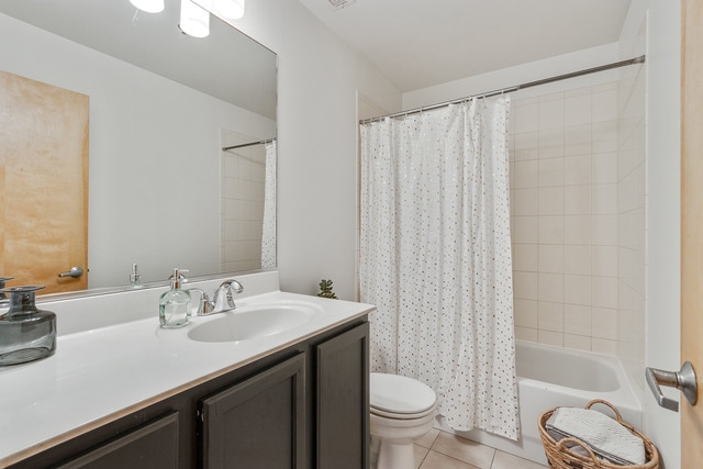 full bathroom featuring shower / bath combo with shower curtain, toilet, vanity, and tile patterned flooring