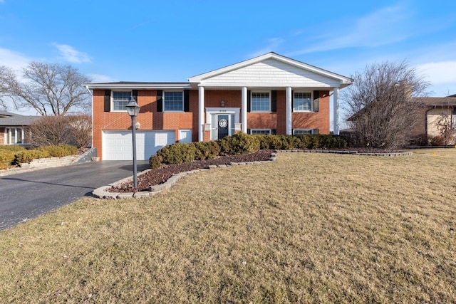 view of front of house with aphalt driveway, a garage, brick siding, and a front yard