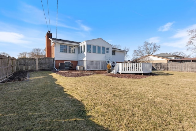 back of property with a lawn, a fenced backyard, a wooden deck, brick siding, and a chimney