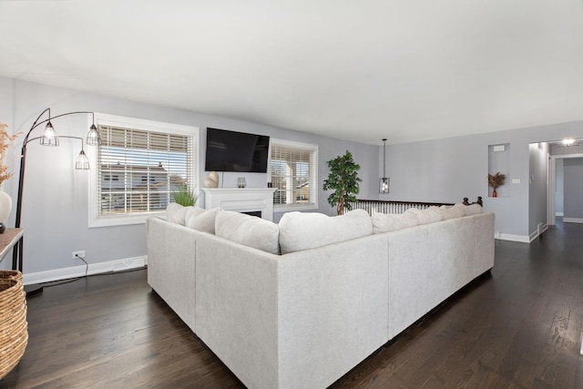 living room with baseboards, a fireplace, and dark wood-style flooring