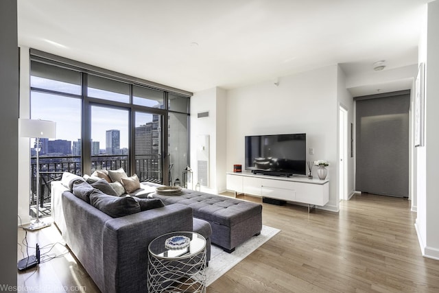 living room featuring visible vents, baseboards, wood finished floors, and expansive windows