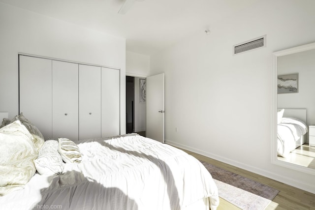 bedroom with visible vents, baseboards, a closet, and wood finished floors