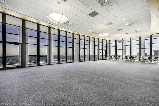 exercise room with visible vents, floor to ceiling windows, a high ceiling, and a drop ceiling