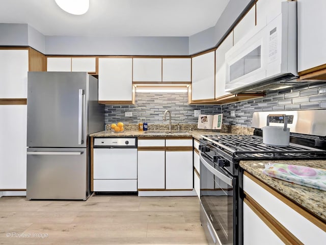 kitchen featuring white cabinets, light wood finished floors, appliances with stainless steel finishes, and a sink