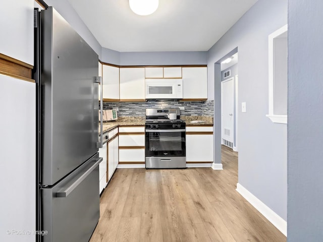 kitchen featuring tasteful backsplash, visible vents, light wood-style flooring, stainless steel appliances, and white cabinetry