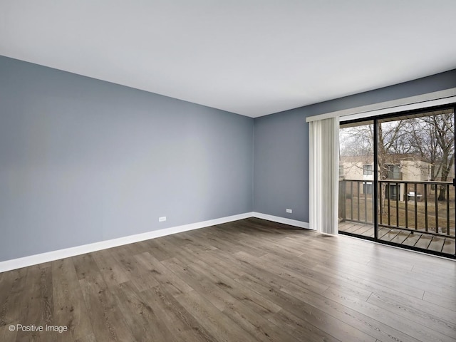 spare room with baseboards and wood finished floors