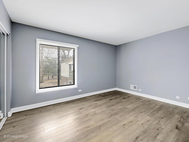 spare room featuring visible vents, baseboards, and wood finished floors