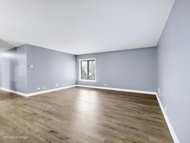 empty room featuring visible vents, baseboards, and wood finished floors