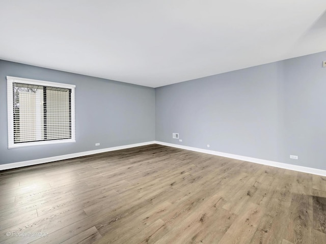 spare room featuring baseboards and wood finished floors