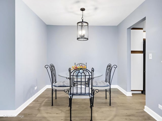 dining room with baseboards, wood finished floors, and a chandelier