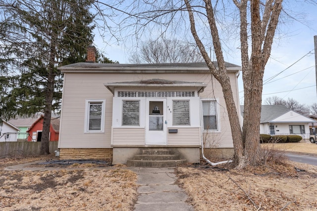 view of front of home with entry steps, fence, and a chimney