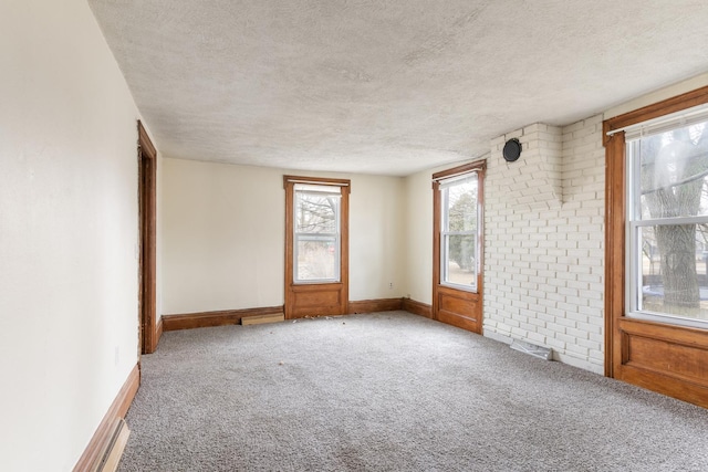 carpeted spare room with visible vents, baseboards, and a textured ceiling