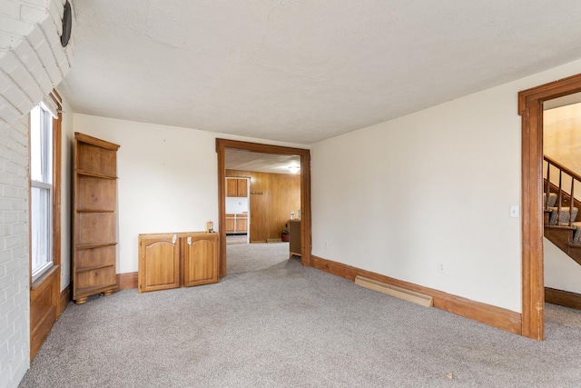 carpeted empty room with stairs, visible vents, and baseboards