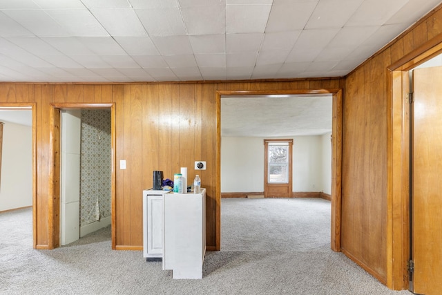 corridor with wooden walls, light colored carpet, and baseboards