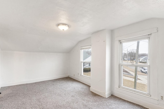 additional living space featuring light colored carpet, baseboards, a textured ceiling, and vaulted ceiling