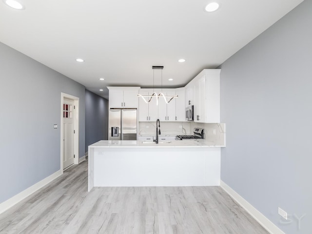 kitchen featuring decorative backsplash, light wood-style flooring, a peninsula, and stainless steel appliances