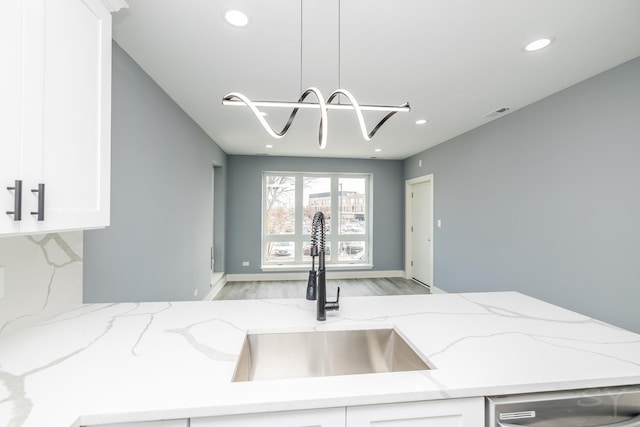 kitchen featuring dishwashing machine, light stone countertops, recessed lighting, a sink, and white cabinetry