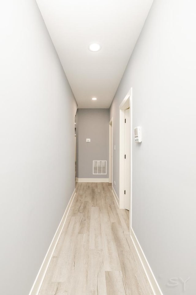 hallway with baseboards, visible vents, and light wood-type flooring