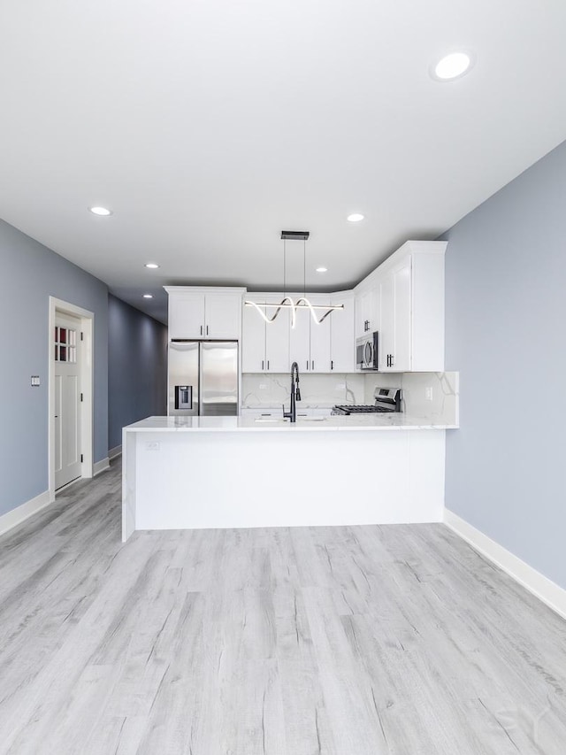 kitchen with a sink, stainless steel appliances, white cabinets, light countertops, and baseboards