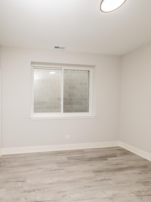 empty room featuring visible vents, light wood-type flooring, and baseboards