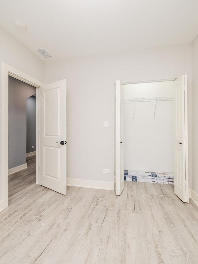 unfurnished bedroom featuring a closet, visible vents, baseboards, and wood finished floors