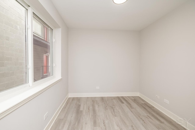 spare room featuring baseboards and light wood finished floors