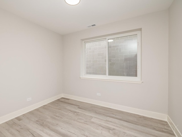 empty room featuring visible vents, baseboards, and light wood finished floors