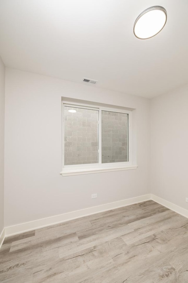 spare room with visible vents, baseboards, and wood finished floors